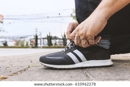 A man tie his sneaker shoes with soft-focus in the background. over light and film colors tone