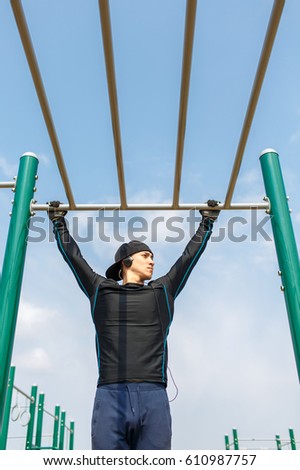 Sporty young man doing exercises on a horizontal bar