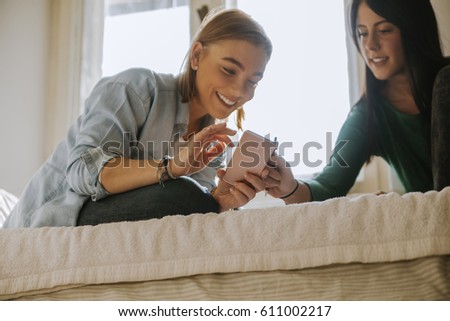 Two Girls Using A Smartphone In The Bedroom