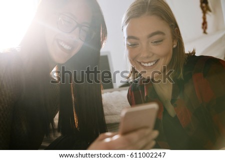 Two Girls Using A Smartphone In The Bedroom And Drinking Coffee