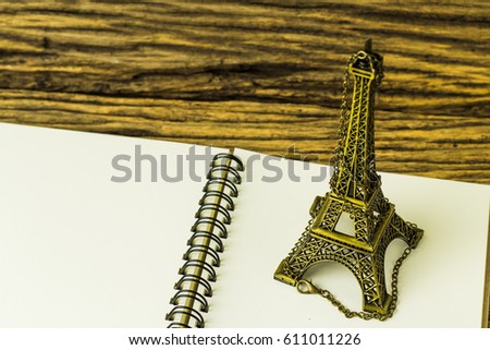 Open book and Eiffel tower replica on wooden background.