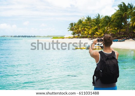 Back view of male tourist taking pictures of tropical beach, admiring nice ocean view