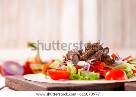 Tacos with Vegetables and Meat against a light wood Background. Selective Focus.