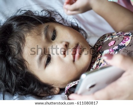 A cute little asian girl is looking at mobile phone, close up