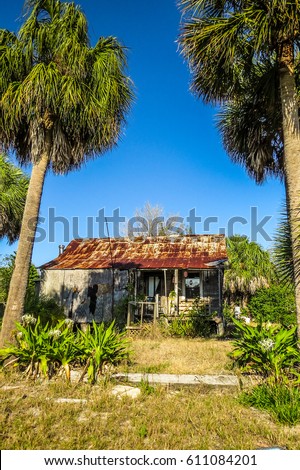 Abandoned shack shadowed with foliage and palm trees, head-on view.   Minimal HDR (High Dynamic Range) effect