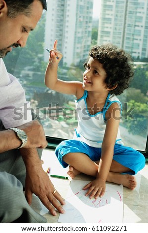 Girl sitting on floor with crayons and paper, looking at father next to her
