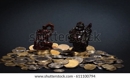 Little statues sitting on a big pile of coins bringing good luck