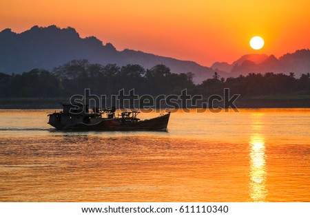 Boat sailing along the river at sunset against the background of mountains
