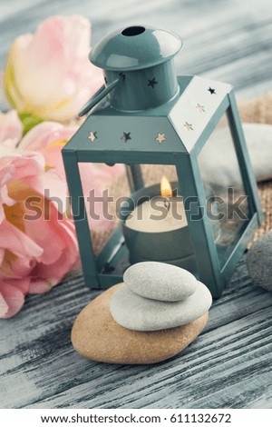 Candle and pebbles over shabby wooden background, copy space