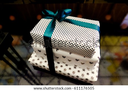 Boxes with gifts packed in black and white paper with a green ribbon