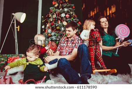 The mother, father and children sitting near Christmas Tree