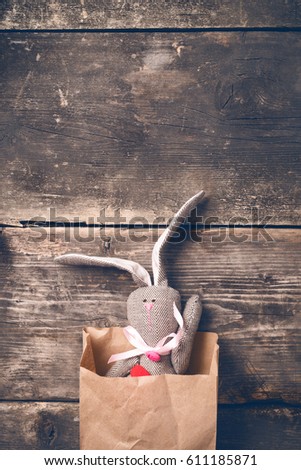Easter bunny in a paper bag on old boards. Rabbit. Old board background. Easter ideas. Easter eggs. Space for text. Image in trendy toning.