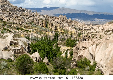 General landscape view of Pigeon Valley in Cappadocia with tufa hills and caves on cloudy sky background.