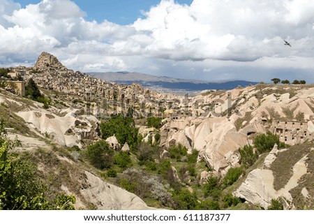 General landscape view of Pigeon Valley in Cappadocia with tufa hills and caves on cloudy sky background.