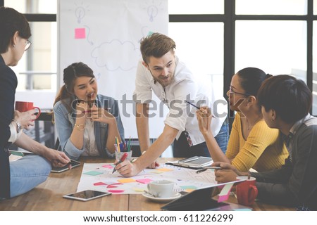 Multiethnic group of happy business people working together, meeting and brainstorming in office. Use computer, laptop, tablet, mobile phone. Royalty-Free Stock Photo #611226299