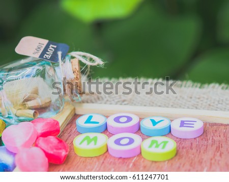 love mom spelled with colorful alphabet blocks and a red heart isolated on wooden board and  sack - Mothers Day