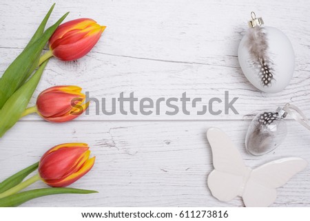 Colored eggs and tulips over wooden background. Easter day photo.