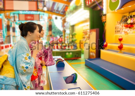 Japanese woman dress traditional kimono and playing hit tumbling dolls called Daruma in a market at Tokyo, japan. Beauty asian girlfriends happy to win at leisure time.