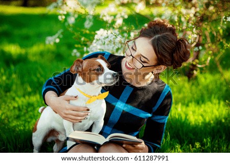 Beautiful young brunette woman enjoying in park outdoors together with her gorgeous Jack Russell terrier.