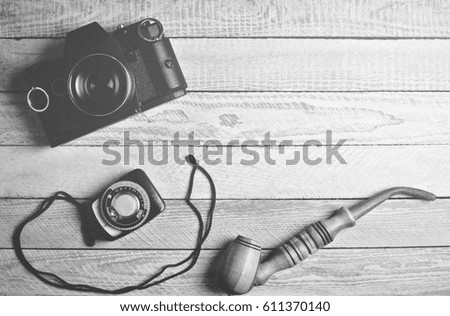 The equipment of the photographer.Film camera, a device for measuring exposure, smoking pipe. Black and white photography.
