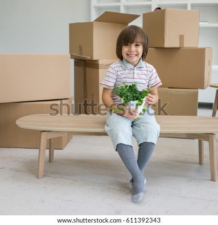 Little cute boy in empty room, remoove to new house home alone between boxes