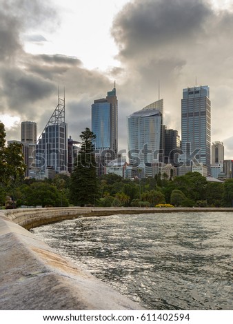 Sydney City, CBD Landmark Cityscape Panorama and Circular Quay Harbour View under Dramatic Sky Golden Sunset Reflected in Sydney Harbour Waters from Mrs Macquarie's Chair in Summer New Year, Australia