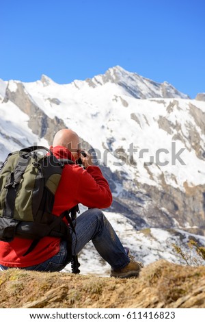man hiker with camera and backpack taking picture of beautiful mountain