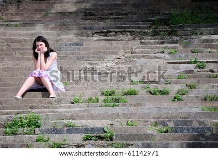 The girl sits on an old ladder and looks in the cam