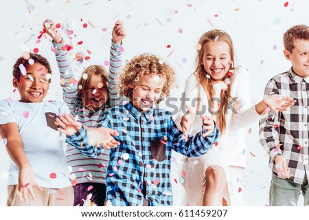 Happy kids throwing colorful confetti in a room Royalty-Free Stock Photo #611459207