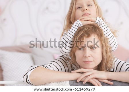 Little girl laying on her angry mom on a bed