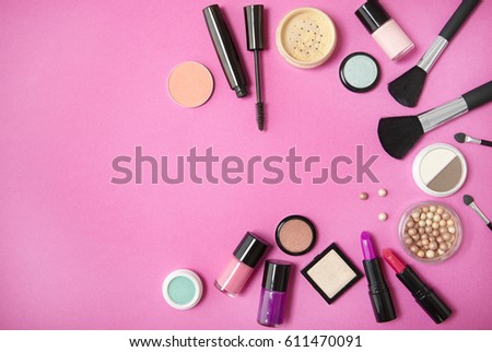 Make up and cosmetic beauty products arranged on a vibrant pink background, with blank space at side