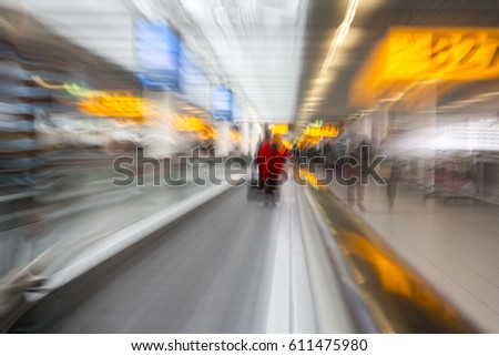 Rushing through the airport terminal to catch the next layover flight. Motion blurry image on an escalator. Last minute hurry to not to be late to the gate and miss the flight. Royalty-Free Stock Photo #611475980