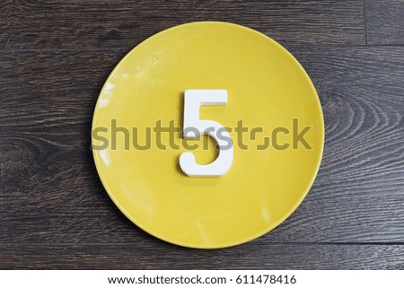 Figure five on the yellow plate and brown background.