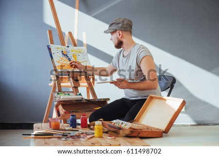 artist painting a picture in a studio.