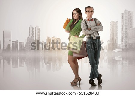 Happy asian woman with shopping bags standing with nerdy man in cityscape background