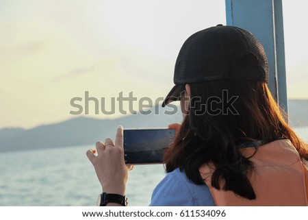 Tourist woman using a cellphone to take a photo with a view of the sea