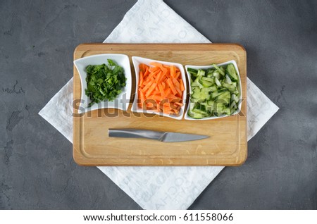 cooking ingridients on the table. Carrots, cucumber and parsley on a cutting board