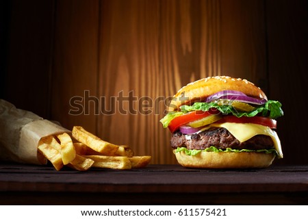 Big hamburger with french fries on wooden background