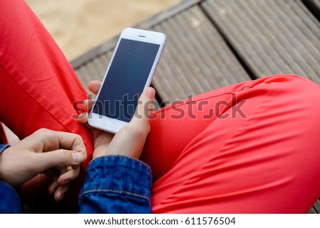 Closeup on woman sitting using mobile phone. Portable computer mockup display on outdoors background