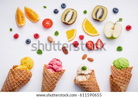 Cones and colorful various fruits raspberry ,blueberry ,strawberry ,orange slice , half kiwi ,apple,tomato and peppermint leaves setup on white background . Summer and Sweet menu concept flat lay.