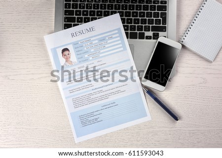 Resume, phone and laptop on wooden table