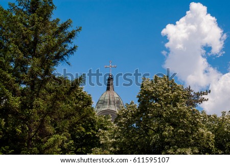 Church tower with a cross with trees and sky composition
