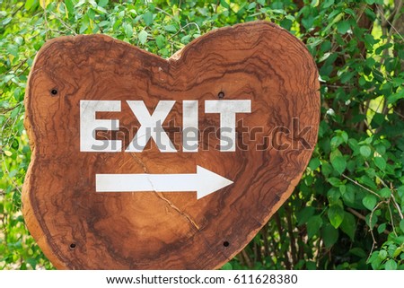 Close up wooden exit sign with trees in background