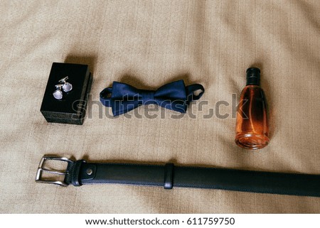 Groom's bowtie, belt, cologne & cuff-links closeup