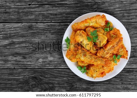 delicious golden batter deep fried fish fillets, served on white plate on old dark wooden worktop, view from above, blank space for text left Royalty-Free Stock Photo #611797295