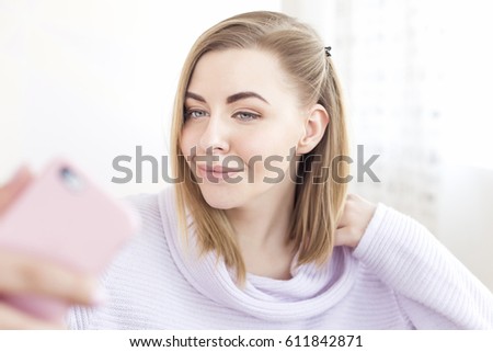 Pretty girl using her smartphone at home, reading messages, smiling