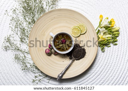 Food background with different black and green dry tea, rose buds cup of hot tea and iron teapot over dark wooden background. Tea drinking concept. Top view. Square image