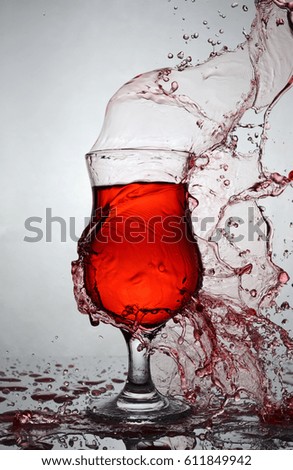 Splash in glass of red alcoholic cocktail drink on gray gradient background