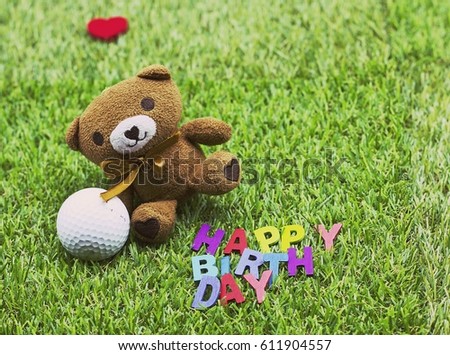 Bear with golf ball and happy birthday letter on green grass