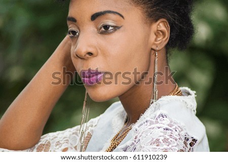 Closeup of beautiful face of pretty woman posing near a foliage